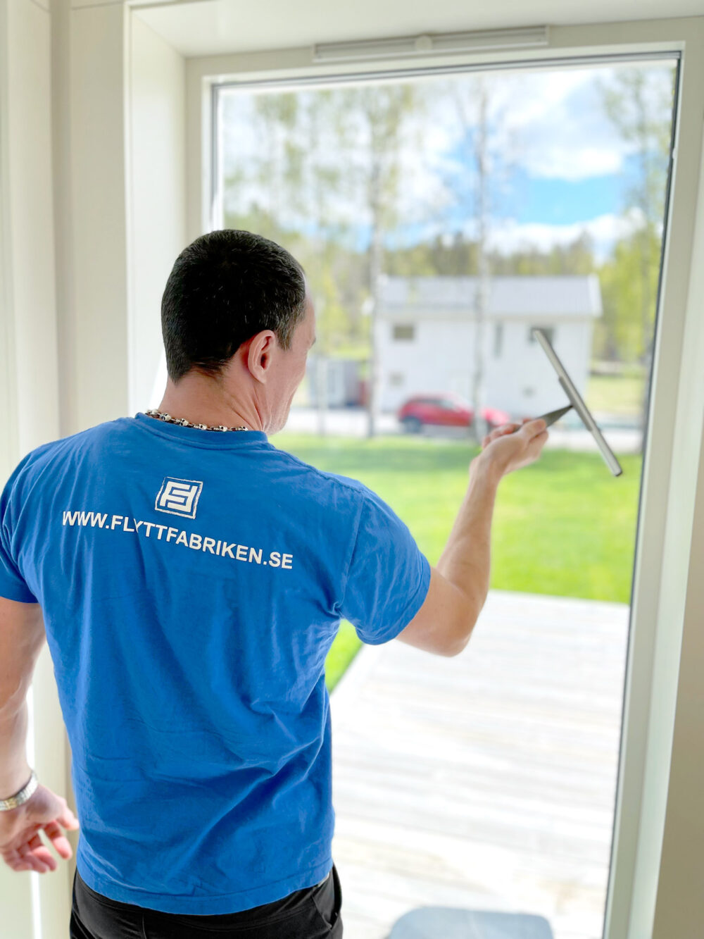Fönsterputsning under flyttstädning i Stockholm utförs av en medarbetare klädd i Flyttfabrikens blå t-shirt.